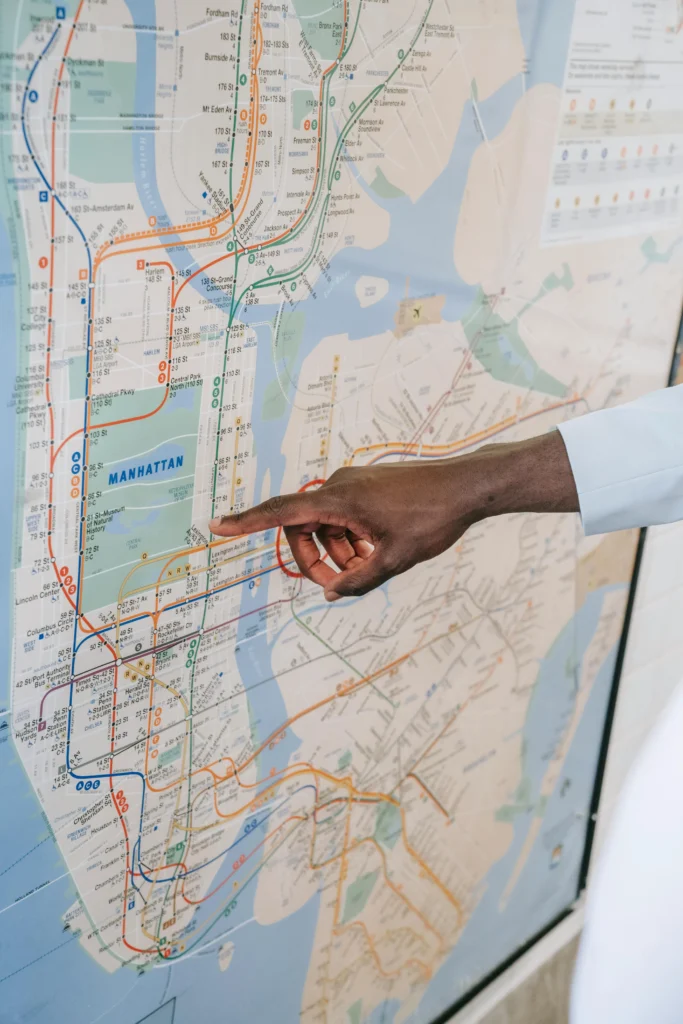 Person pointing to Manhattan route on New York City subway map.